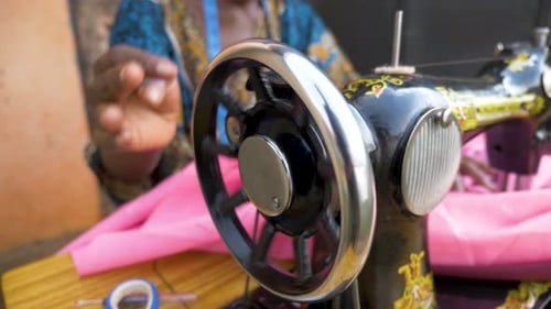 Close up slow motion shot of an African womans hands spinning the wheel on a manual operating tailor
