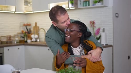 Affectionate Couple Embracing and Kissing in a Modern Kitchen