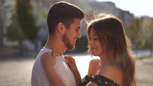 Side View Closeup Laughing Loving Young Couple Hugging Standing in Sunrays on City Street
