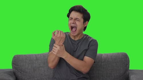 Sick Indian man suffering from wrist pain Green screen