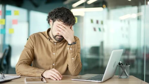 Stressed Man Suffering Headache at Office Desk