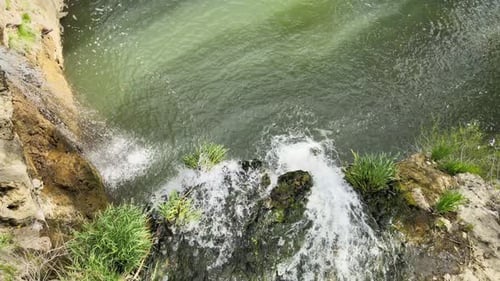 Picturesque Waterfall Flowing Into a Small Green Pond