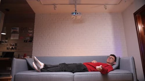 Young Adult Relaxing with Projector on Couch