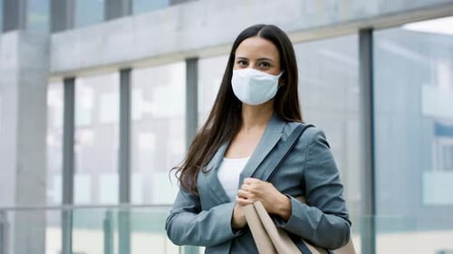 Businesswoman in face mask at airport on business trip looks at camera confidently