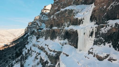 Drohnenaufnahme eines professionellen Bergsteigers, der auf Eis und verschneiter Bergwand klettert