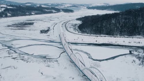Aerial View of Snow-Covered Railroad Bridge Over Frozen Lake