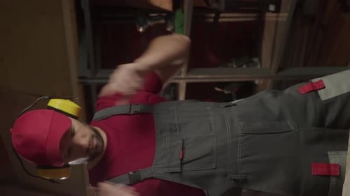 Young Adult Puts on Headphones and Uses Drill