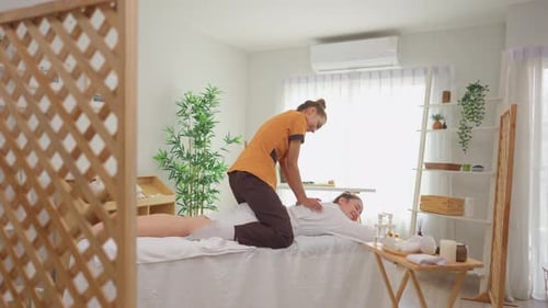 Beautiful woman in bathrobe getting back massage treatment at beauty spa.