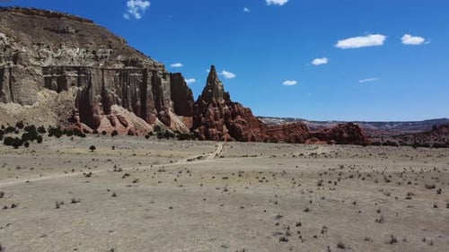 A desert crossed by a road, bordered by high cliffs, in broad daylight, bird's eye view fast motion