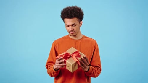 Happy African American Man Examines Gift Box with Red Bow