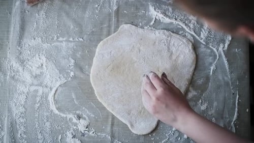 Woman rolls out dough with a rolling pin