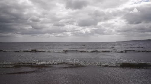 A dramatic skyline over the sea from the shoreline, waves lap at the shore.