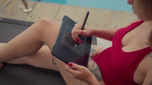 Woman Drawing on Tablet by Swimming Pool