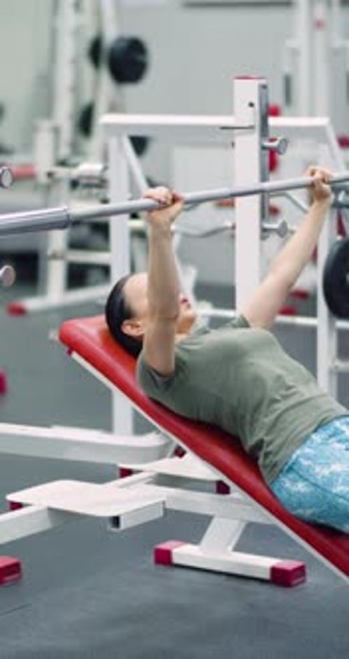 Woman Bench Pressing Barbell in Gym Workout