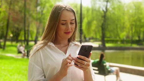 Woman Using Smartphone in Park on Sunny Day