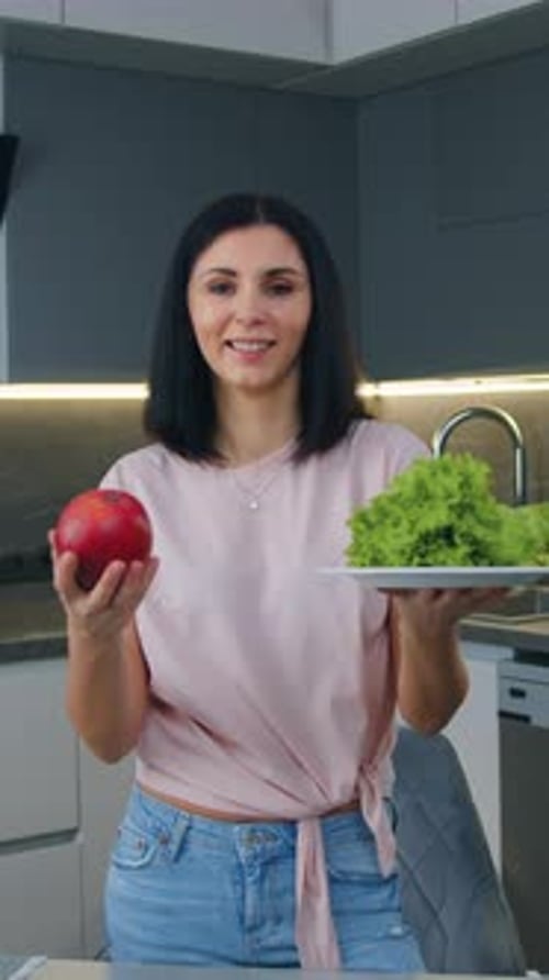 Woman Holds Apple and Lettuce in Modern Kitchen