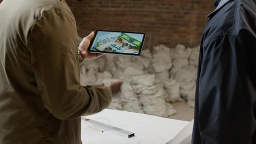 Architects Discussing Plan of Office Renovation Using Tablet and Blueprint