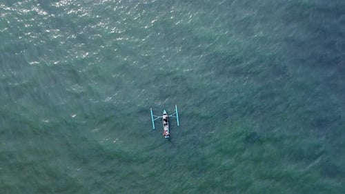 Paisaje aéreo: un pequeño y solitario barco pesquero tradicional Jukung a la deriva en un día soleado en un azul profundo