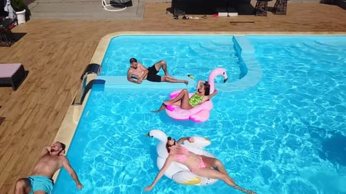 Friends Relaxing on Inflatables in a Swimming Pool