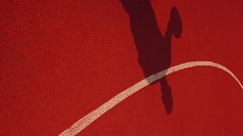Close-up of a basketball guy's shadow on the floor of a basketball court while dribbling the ball