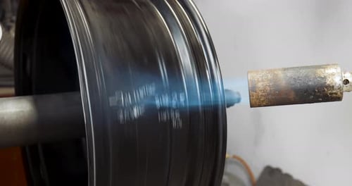 Wheel spins slowly automatically while a blowtorch heats it up before it gets straightened. 4k close
