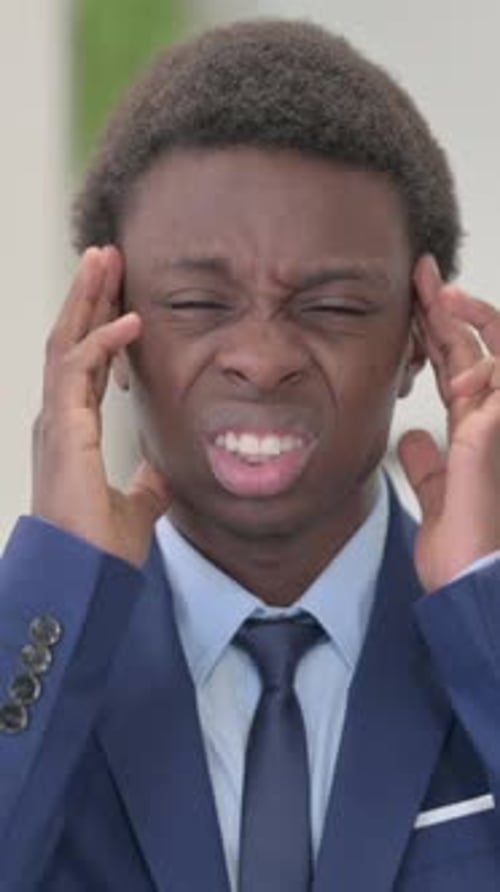 Young Man in Suit Massaging Temples Due to Headache