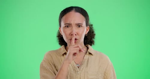 Girl, shh and finger on mouth for quiet, silence and whisper on green screen in studio with upset