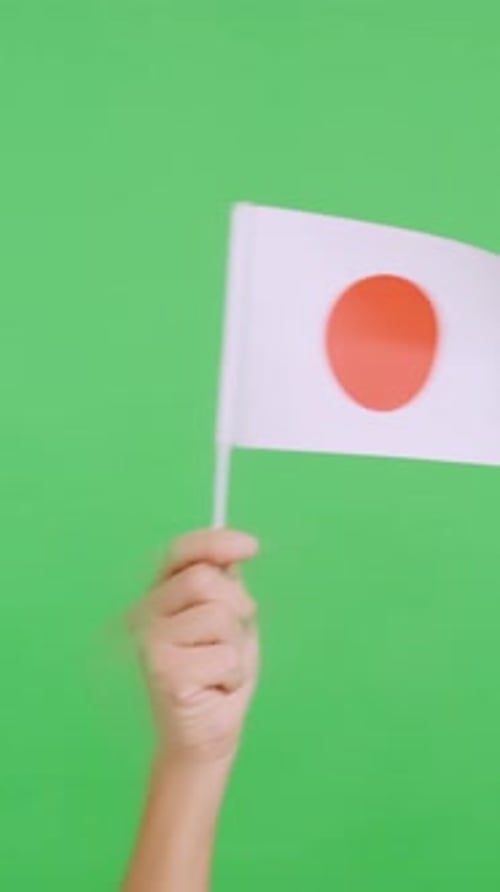 Einen Wimpel einer japanischen Nationalflagge mit der Hand schwenken