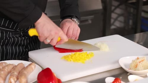 Chef dices red peppers on a cutting board