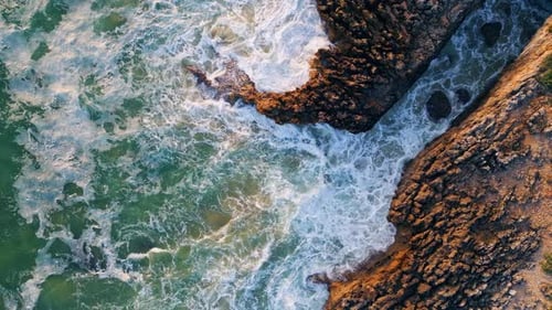 Tormentoso oleaje oceánico rodando en la costa volcánica, acantilados, cámara lenta, vista aérea desde arriba