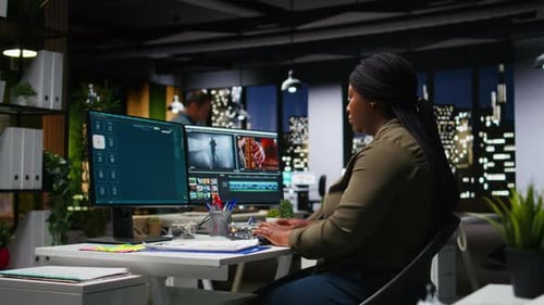 Young Black Woman Video Editor Working with Dual Monitors in Creative Agency