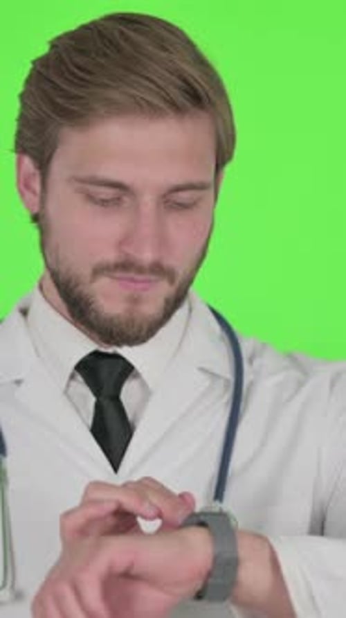 Young Doctor Using Smartwatch on Green Background, Vertical Video