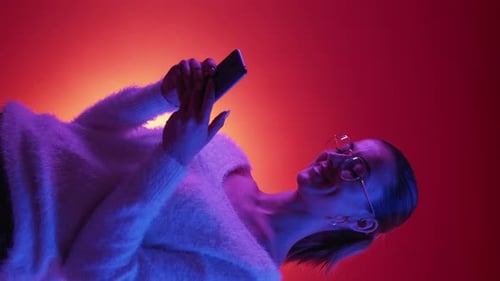 Woman Using Mobile Phone in Red and Blue Lighting