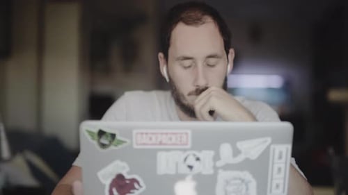 Young Man Uses Laptop in Indoor Setting