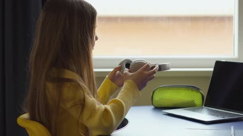Teen Puts on Headphones to Study at Laptop