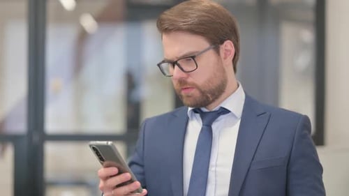 Man in Suit Using Smartphone in Office