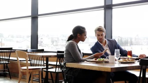 Business people collaborate over lunch in restaurant using smart phones