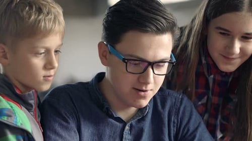 Happy Children Talking and Browsing Internet on Tablet by Table at Home Adolescent