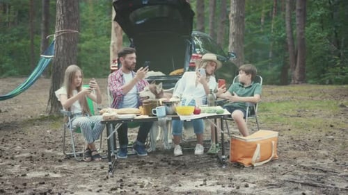Family at Picnic Table Talking on Phones in Forest
