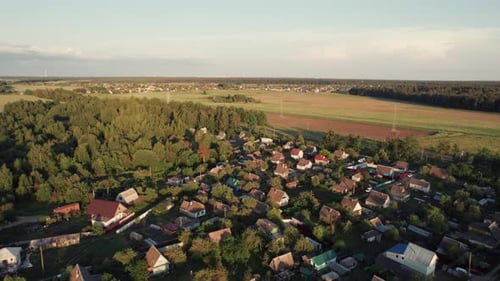 Top View of a Village in a Forest with Modern Buildings and Yards Near an Asphalt Road