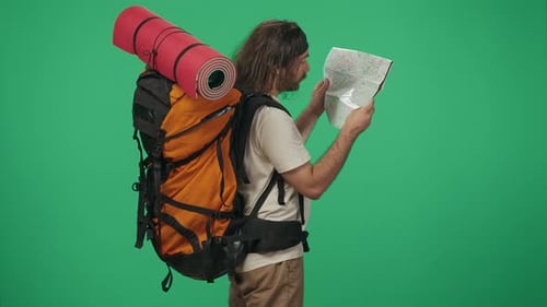 Man Tourist with Backpack Holding Paper Map Looking at It Reading the Signs Finding Direction