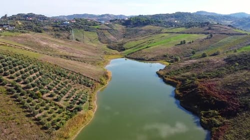 Drone view above scenic lake inside the albanian countryside during daytime.