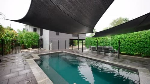 Pullback above elegant luxury pool and shade covering draped over outside on rainy day. Exterior of