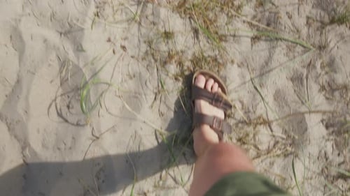 Footsteps on sandy beach with sparse grass. Perfect for travel videos and vacation promotions. Male