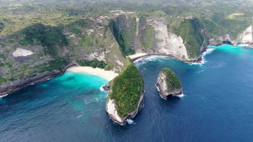 Majestic view of Nusa Penida island with tall cliff and sandy beaches, aerial orbit view