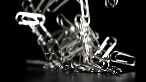 Silver Paper Clips Falling in Slow Motion on Black