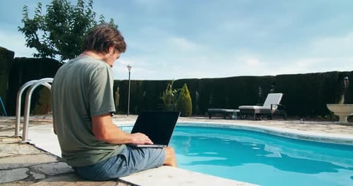 Man Sit on Poolside Typing on Laptop Computer Keyboard at Summer Vacation Trip