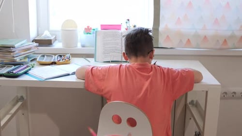 Boy Doing Homework at Desk in Bright Room