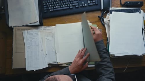 Office worker audits archive document files on desktop TOP DOWN view