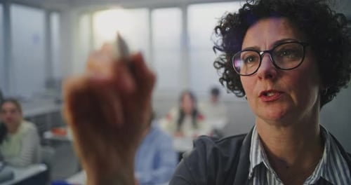 Erwachsene Brillenträgerin schreibt aktiv mit Marker auf unsichtbarer interaktiver Tafel